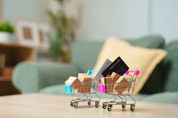 Miniature shopping carts with parcel boxes and credit cards on table, online shopping, e-commerce, cashless payment, digital retail, consumer spending, online checkout and delivery © Joi_studio