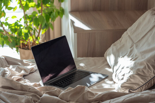Laptop resting on bed a morning remote work setup