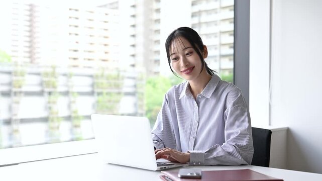 笑顔でノートパソコンを使う30代日本人女性