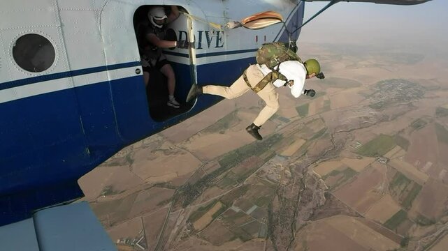 Man jumps out of a plane with a parachute.