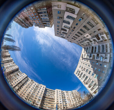 Fisheye view of residential apartment buildings looking up at blue sky in post soviet city
