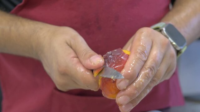 A ripe peach is peeled with care to prepare fresh ingredients for cocktails and refreshing drinks served at a catered celebration