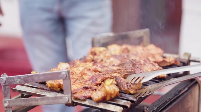 Close Up of Hand Turning Seasoned Chicken on Barbecue Grill with Tongs