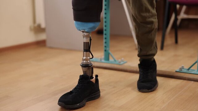 prosthetic leg, mobility recovery, therapist guidance. Physical therapist assists patient with prosthetic leg during rehabilitation session, patient uses parallel bars to practice walking