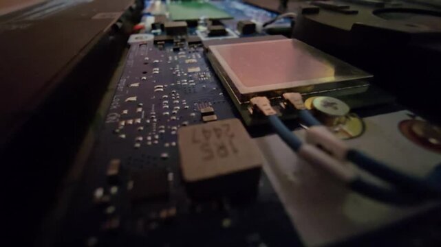 Close-up shot of a laptop Wi-Fi card with antenna wires and electronic power management components on the motherboard.