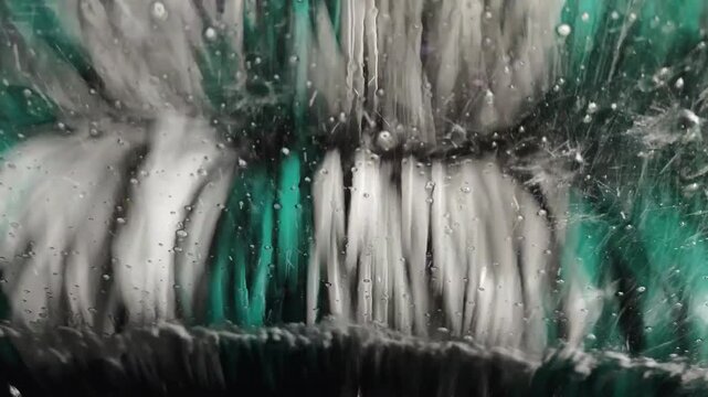 Close up video from inside a car windshield during an automatic car wash with rotating cloth brushes and water splashing on the glass.
