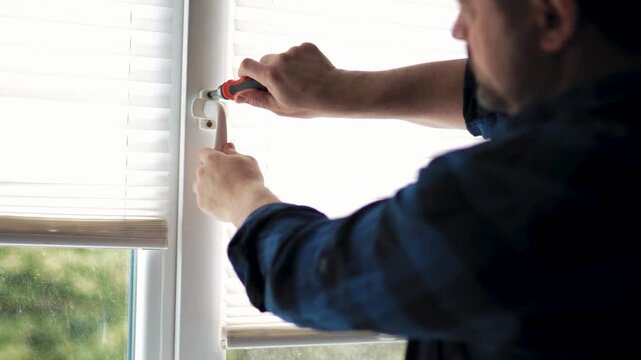 Close up of hands tightening a screw on a pvc window handle with a hand tool