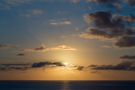 Sole al tramonto coperto dalle nuvole sul mare