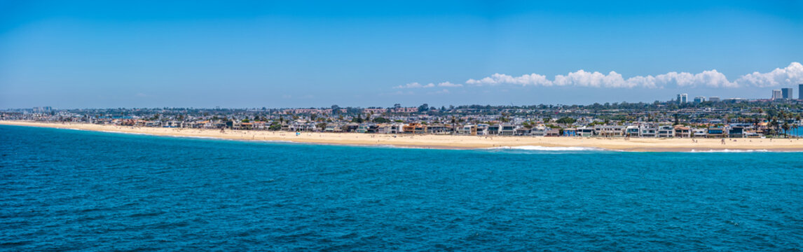 panoramic aerial landscape view of Balboa Beach located on Harbor Island, a small artificial island in Newport Beach, California, with a wide sandy beach and people sunbathing, Newport Beach cityscape