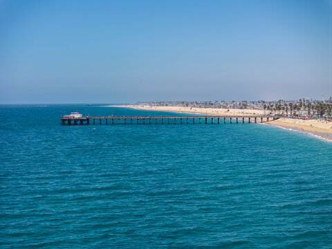 aerial landscape view along Balboa Beach, with Newport Beach Balboa Pier, located on Balboa Peninsula, an artificial island in Newport Beach, California - people sunbathing on the beach and swimming