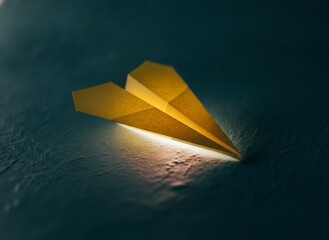 Yellow paper airplane on textured surface with soft lighting