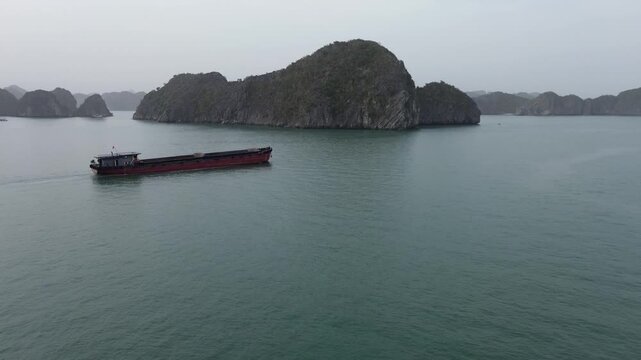 Majestic aerial view of a large cargo vessel sailing through the iconic karst landscape of halong bay