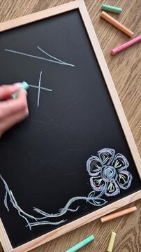 Hand drawing division symbol with colorful chalk on blackboard
