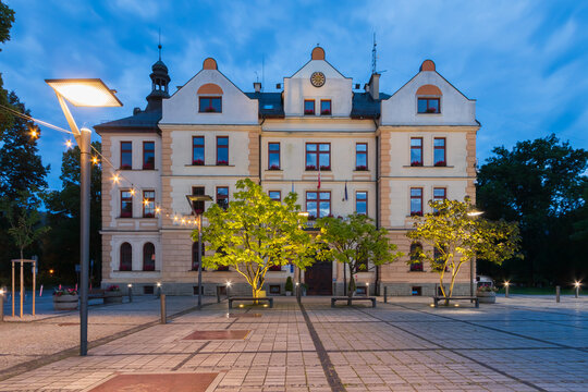 Illuminated Town Hall (Urzad Miasta) building at dusk on the main square in Ustron, Poland.