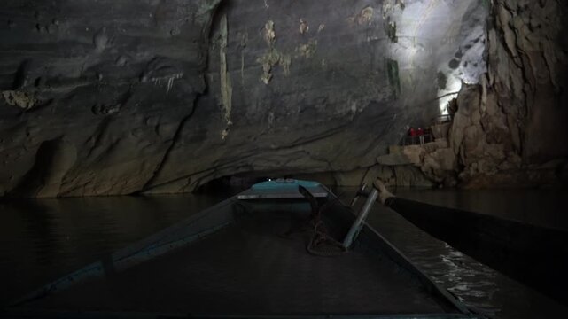 Point of view from a tourist boat sailing on an underground river through a dark, ancient cave