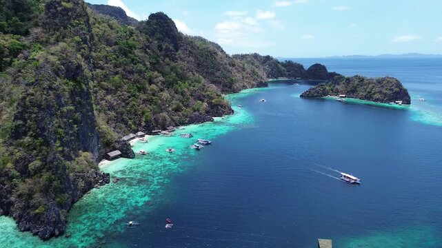 Boats sailing on a turquoise lagoon surrounded by tropical forest and limestone cliffs in palawan