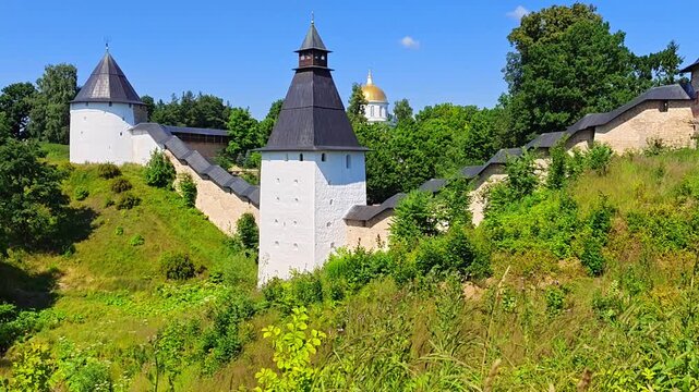 The walls and tower of the ancient Pskov-Pechersky Monastery and a view of St. Michael's Cathedral. Pechory, Russia
