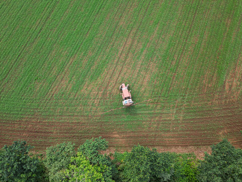 Tractor cultivating green field from aerial view