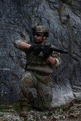 Fototapeta premium Military squad in camouflage uniforms conducts tactical field training in rocky terrain. Concept of teamwork, defense, security, combat readiness, and military operations.