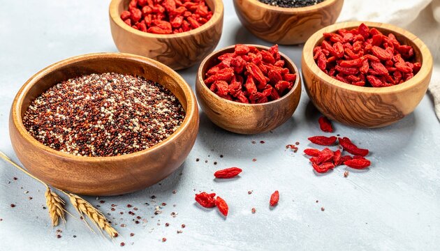 Quinoa and Goji Berries in Wooden Bowls on Grey Background