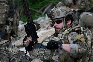 Obraz premium Focused military infantry soldier lying prone on rugged rocky terrain aiming a tactical assault rifle during a dangerous combat training mission for national defense and special security.