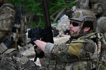 Fototapeta premium Focused military infantry soldier lying prone on rugged rocky terrain aiming a tactical assault rifle during a dangerous combat training mission for national defense and special security.