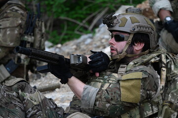Obraz premium Focused military infantry soldier lying prone on rugged rocky terrain aiming a tactical assault rifle during a dangerous combat training mission for national defense and special security.