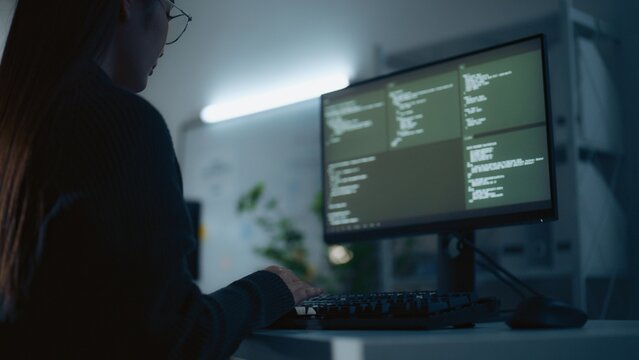 Asian female software developer writing code computer modern technology office at night representing software development programming cybersecurity artificial intelligence and digital innovation