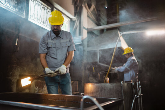 foundry steel melt manufactory iron worker Industrial workers operating molten metal in a foundry while wearing protective equipment highlighting manufacturing workplace safety and heavy industry