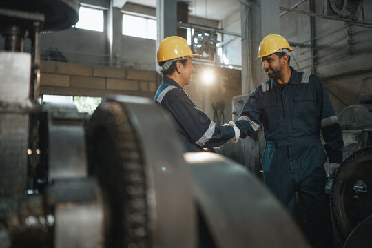 teamwork management worker manager entrepreneur planning Industrial workers shaking hands inside a manufacturing factory symbolizing teamwork leadership workplace collaboration and production success