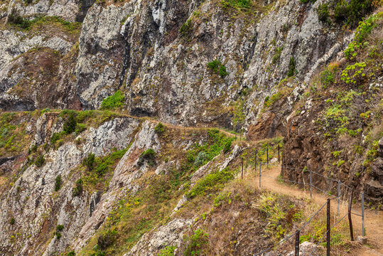 Narrow cliff-edge hiking path carved into the rock on the Vereda do Larano, Madeira