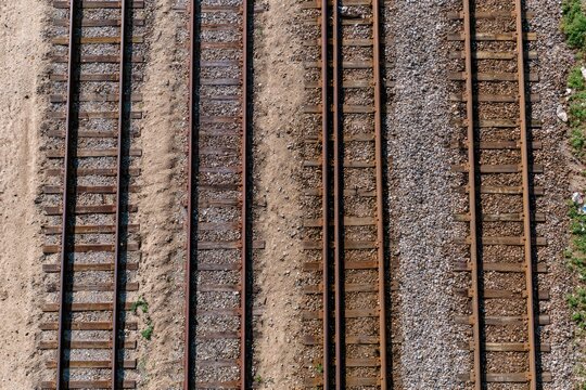 Overhead view of multiple weathered train tracks on gravel and sand