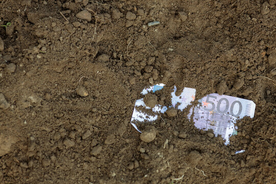 Partially Buried 500 Euro Note in Dark Soil