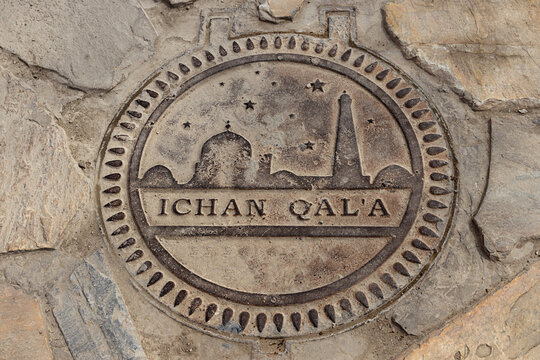 Ichan Qala metal medallion embedded in stone pavement showing the iconic skyline silhouette of Khiva old town. Decorative ground marker ideal for travel guides, heritage publications, and tourism.