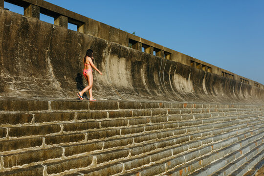Girl walking Along Seaside Wall