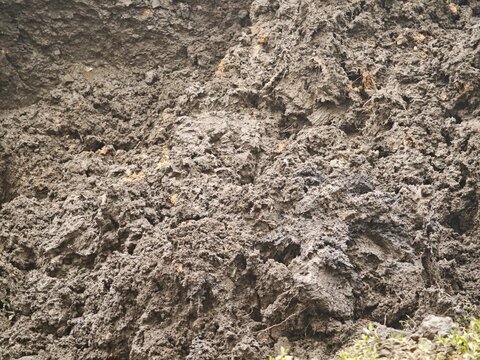 Macro texture of wet excavated earth with mud clumps at a construction site.