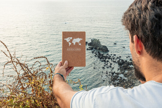 Man holding adventure notebook dreaming of travel by ocean