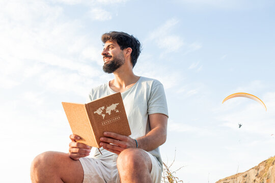 Man holding travel journal dreaming of adventure