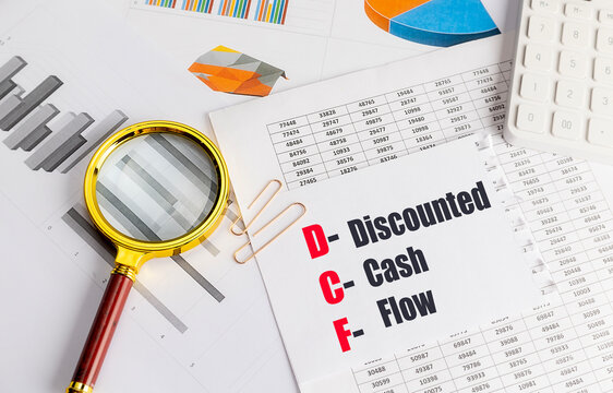 Discounted cash flow dcf acronym on financial documents with magnifying glass calculator and charts representing business valuation
