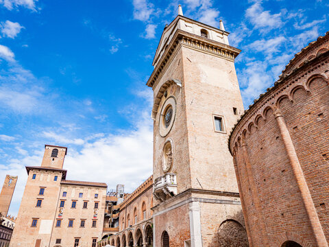 Observing the historic Torre dell'Orologio and neighboring medieval architecture in Mantova, Italy, highlighting the city's rich history and cultural heritage under a clear sky