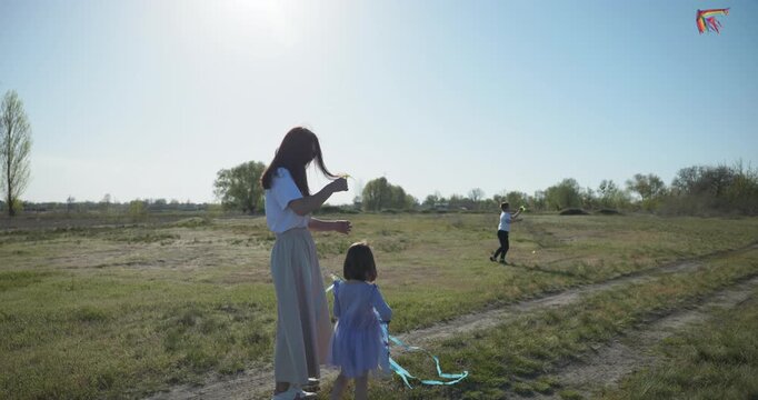 Children with mother flying a kite. Family spend time together on nature. 4K 10-bit