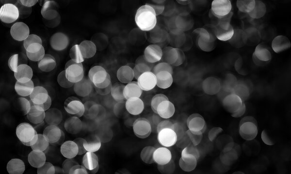 Monochrome bokeh background with blurry silver lights out of focus on black texture. Elegant minimalist event banner.