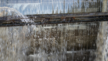 Water cascading down a low head dam or water management system, creating a curtain effect. floodgate metaphor background. © mailcaroline