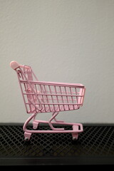Empty pink toy shopping cart on black surface with copy space, shopping concept © Stanislava