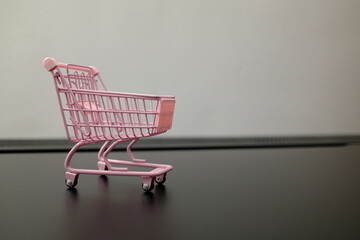 Empty pink toy shopping cart on black surface with copy space, shopping concept © Stanislava