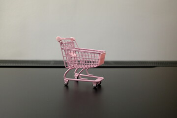 Empty pink toy shopping cart on black surface with copy space, shopping concept © Stanislava