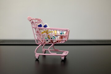 Rolled 10 euro banknotes in pink toy shopping cart on dark surface with copy space © Stanislava