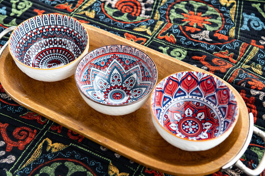 Decorative ceramic bowl set with colorful traditional patterns displayed on wooden serving tray