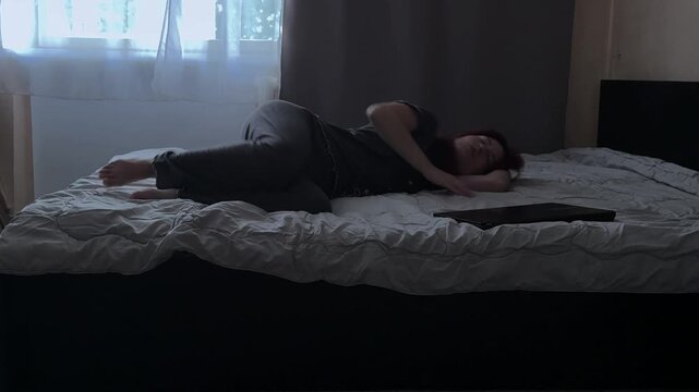 Depressed Woman Closing Laptop on Bed Side View