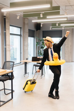 Businessman celebrating vacation with suitcase and duck float